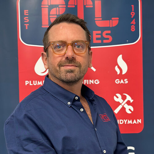 Ben L'Estrange standing in front of a sign with RTL Trades logo on it